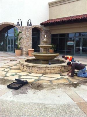Workers placing paving stones around a fountain